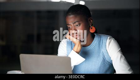 Ennuyé, ordinateur portable et nuit avec une femme noire d'affaires au bureau pour la planification ou la date limite de recherche. Ordinateur, la lecture et fatigué avec l'employé africain à Banque D'Images