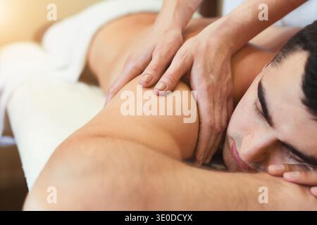 Masseur faisant massage des épaules sur le corps de l'homme Banque D'Images