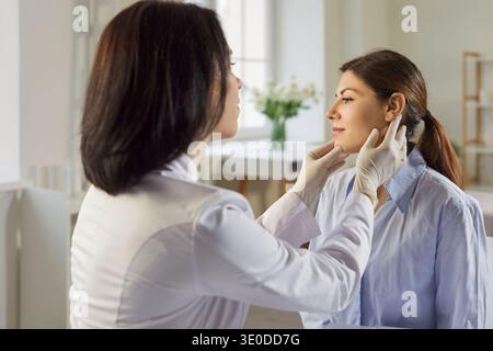 Dermatologue vérifiant le visage de la patiente lors d'une consultation de soins en clinique Banque D'Images