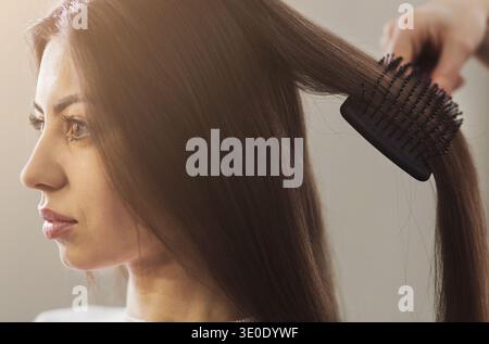 Coiffeur peignant les cheveux de femme dans un salon professionnel Banque D'Images