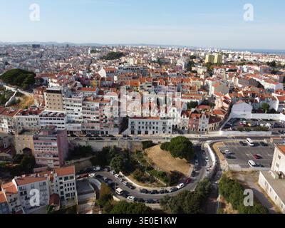 Vue aérienne des toits en terre cuite en cascade vers des routes sinueuses bordées d'arbres verdoyants, une tapisserie vibrante sous un ciel clair, Lisbonne, Lisbonne, Por Banque D'Images
