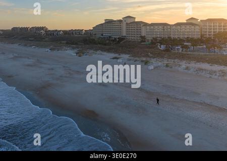 Vue aérienne d'une figure solitaire se promenant le long de la côte sablonneuse tandis que de douces vagues embrassent le littoral, avec de grands hôtels debout, Amelia Island, Flor Banque D'Images