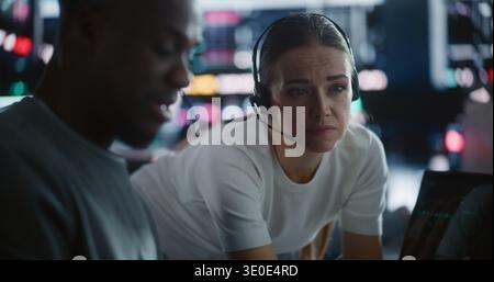 Les traders d'équipe diversifiés discutent de stratégie de marché urgente pendant la volatilité. Un trader masculin et un collègue féminin collaborent intensément dans Futuristic Financial Hub. Concept de gestion collaborative de crise. Banque D'Images