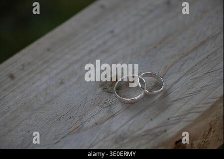 Deux bagues de mariage simples en argent reposant sur une surface en bois rustique symbolisant l'engagement intemporel et l'unité. Banque D'Images