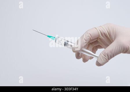 Main gantée tenant la seringue prête pour l'injection, la vaccination de soins de santé et le concept de procédure médicale Banque D'Images