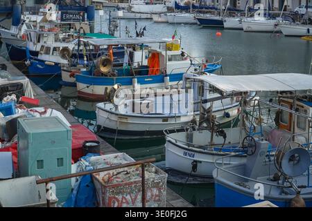 Bateaux de pêche amarrés au quai de Porto Antico, Gênes, Italie. Petits navires commerciaux dans le port pendant la saison froide. Banque D'Images