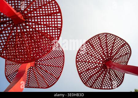 Une vue à angle bas de structures circulaires rouges dans un cadre de parc. L'image véhicule l'expression artistique, le design moderne et des éléments architecturaux audacieux. Banque D'Images