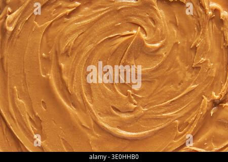 Texture lisse à tartiner au beurre d'arachide avec motifs tourbillonnants pour la publicité culinaire et alimentaire. Banque D'Images
