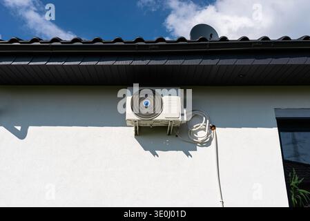 Unité de climatisation moderne montée sur un extérieur de bâtiment résidentiel blanc Banque D'Images