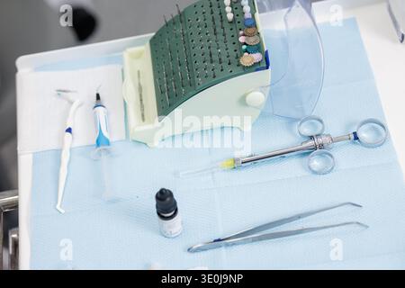 Gros plan de seringue dentaire, applicateur composite, support de fraises et instruments sur plateau stérile dans la clinique dentaire moderne. Santé intérieure horizontale equ Banque D'Images