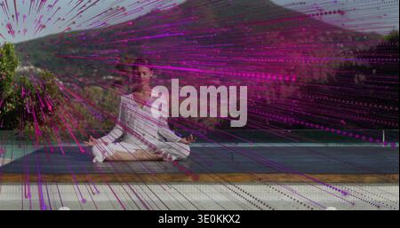 Méditante adolescente en blanc assis les jambes croisées sur le pont, avec tapis foncé et recouvrement magenta Banque D'Images