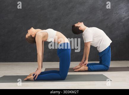 Jeune couple pratiquant le yoga ensemble dans la salle de gym Banque D'Images