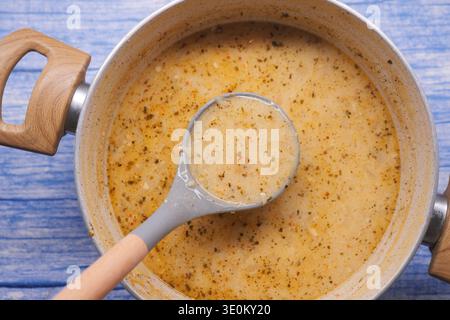 Cuisson de la soupe dans une casserole sur un comptoir de cuisine près du bois bleu Banque D'Images
