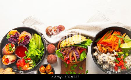 Cuisine vietnamienne, rouleaux de printemps frais, soupes savoureuses et plats variés sur fond clair. Vue de dessus. Banque D'Images