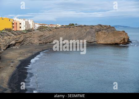 Vue sur la crique de plage de la Conque avec rivage de sable sombre, falaises en couches et mer calme au Cap d'Agde, Hérault, sud de la France. Banque D'Images