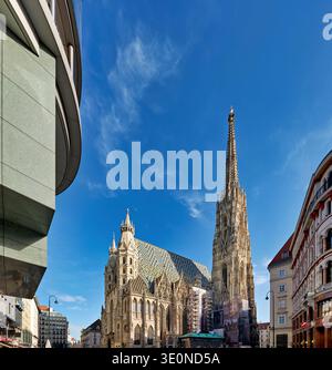 La cathédrale d'Étienne se dresse haut contre un ciel bleu clair à Vienne. Le point de repère est entouré de bâtiments de styles différents. Banque D'Images