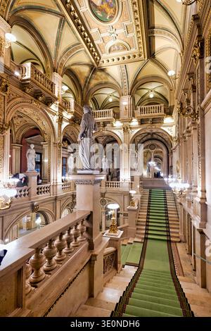 Les gens apprécient l'intérieur historique de l'Opéra national de Vienne. Le grand escalier et les statues attirent l'attention de la foule. Banque D'Images
