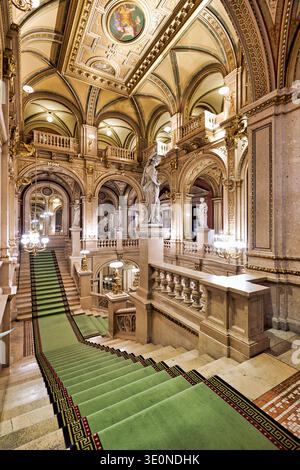 Les visiteurs montent le grand escalier de l'Opéra national de Vienne en Autriche. Statues et décor rehaussent la beauté de ce lieu historique. Banque D'Images