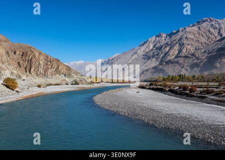 La rivière Nubra turquoise coule à travers un large lit de gravier devant des arbres automnaux et des montagnes arides dans la vallée près de Panamik. Banque D'Images
