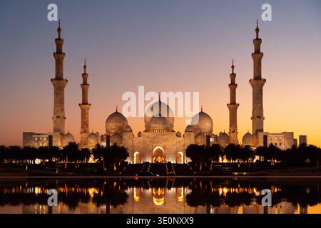 Vue aérienne de la majestueuse Mosquée Sheikh Zayed reflétant dans les eaux calmes au coucher du soleil, Abu Dhabi, Émirats arabes Unis. Banque D'Images