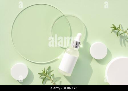 Fond vert menthe frais avec bouteille compte-gouttes de sérum et disques transparents en verre, pots de crème et brin de romarin. Concept de spa. Vue de dessus avec s Banque D'Images