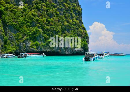 Bateaux à longue queue et touristes entrant dans les eaux turquoises de la baie de Maya sur Ko Phi Phi Leh dans la province de Krabi, en Thaïlande, entourés de calcaires spectaculaires Banque D'Images