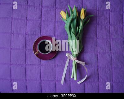 Bouquet de tulipes jaunes et tasse à café vintage sur couverture violette – Flat Lay Cozy Morning Scene Banque D'Images