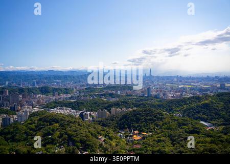 vue panoramique surplombant tout le bassin de Taipei, avec Taipei 101, horizon de la ville niché entre collines verdoyantes et montagnes lointaines sous le ciel bleu Banque D'Images