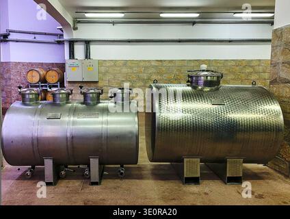 Venets, Bulgarie - 08 octobre 2024 : des réservoirs de transport de vin en acier inoxydable sont positionnés dans une cave avec des fûts en bois et un panneau de contrôle en t Banque D'Images