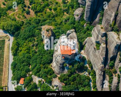 Vue aérienne du Saint Monastère de Rousanou est perché dramatiquement au sommet d'une formation rocheuse imposante, entourée de feuillage vert luxuriant, Météores, Trik Banque D'Images