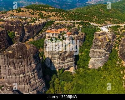 Vue aérienne du monastère de Rousanou perché au sommet d'une formation rocheuse imposante au milieu de paysages verdoyants, Météores, Trikala, Grèce. Banque D'Images