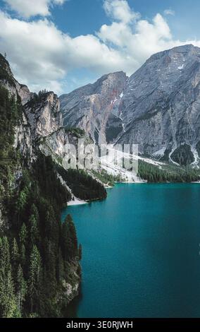 Vue aérienne du lac turquoise vif reflétant les montagnes escarpées des Dolomites, encadrées par des forêts verdoyantes, lac Braies, Trentino-Tyrol du Sud, Ita Banque D'Images