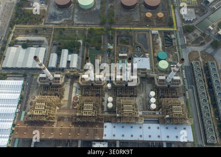 Vue aérienne du paysage industriel sombre, où les cheminées imposantes traversent le ciel au-dessus de structures complexes, créant une symphonie de formes géométriques Banque D'Images