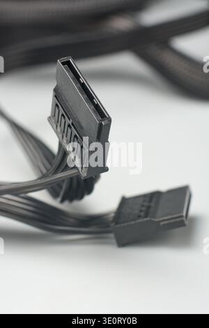 connecteurs d'alimentation sata noirs sur surface grise, plusieurs câbles plats pour le stockage de données, vue latérale avec mise au point souple, assemblage et réparation de l'ordinateur Banque D'Images