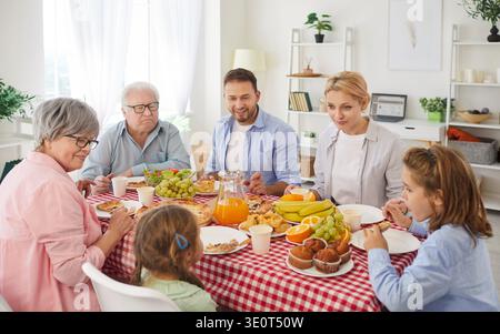 Grande famille heureuse appréciant le dîner ensemble assis à table pendant la célébration des fêtes à la maison. Banque D'Images