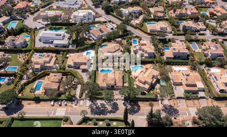 Vue aérienne montre de nombreuses maisons avec piscines entourées d'arbres et de routes dans un quartier résidentiel par une journée ensoleillée. Les gens aiment les activités de plein air Banque D'Images