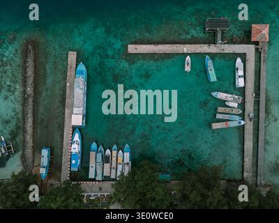Un drone aérien capture un port pittoresque rempli de différents bateaux ancrés dans des eaux turquoises époustouflantes et limpides. L'environnement marin vibrant Banque D'Images