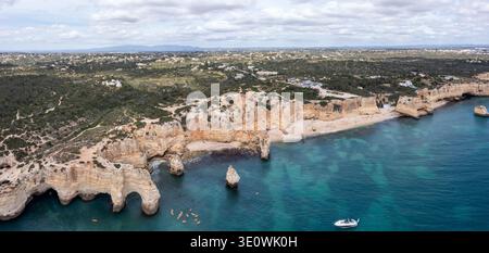 Une vue aérienne panoramique à couper le souffle met en valeur les légendaires falaises de calcaire doré et les eaux turquoises de Praia da Marinha. La côte accidentée Banque D'Images