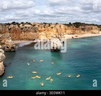 Une vue surélevée met en valeur les falaises calcaires à couper le souffle et les eaux turquoises de Praia da Marinha dans la région de l'Algarve. Nombreux kayaks colorés Banque D'Images