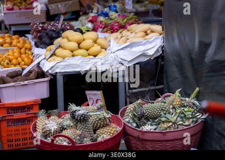 Bangkok Thaïlande 16 janvier 2026. Ananas mangues kaki et autres fruits exposés dans des paniers et sur des tables à l'intérieur du marché Khlong Toei. Banque D'Images