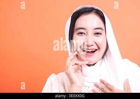 Une femme musulmane rayonnante rayonne de bonheur, son sourire illuminant le cadre, mettant en valeur une expression positive et une élégance culturelle, isolée sur une salle d’opération Banque D'Images