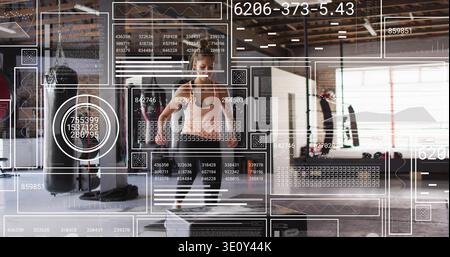Femme sautant portant un soutien-gorge de sport et des leggings, faisant le saut de boîte à la salle de gym d'entrepôt avec AR HUD Banque D'Images