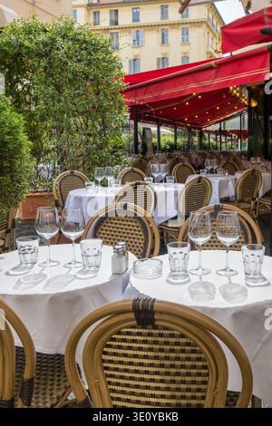 Restaurant extérieur avec auvents rouges et chaises en osier Banque D'Images