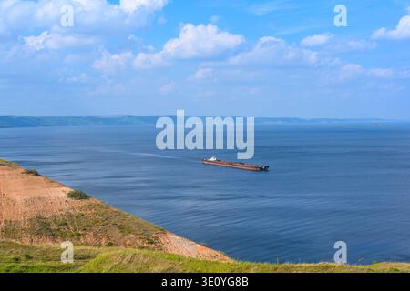 Un remorqueur articulé et un vraquier à barge transportent du sable et des matériaux de construction sur la rivière. La grande barge navigue le long de la large rive de la Volga Banque D'Images