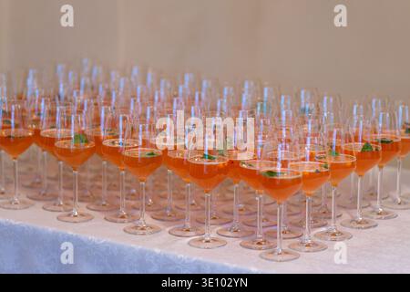 Rangées de cocktails de bienvenue avec jus d'argousier et menthe fraîche servis dans des verres à vin lors d'un événement traiteur. Boissons rafraîchissantes de bienvenue à l'argousier. Banque D'Images