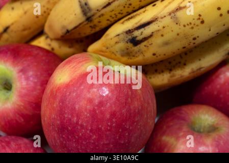 Vue latérale rapprochée des bananes jaunes mûres et des pommes rouges. Banque D'Images