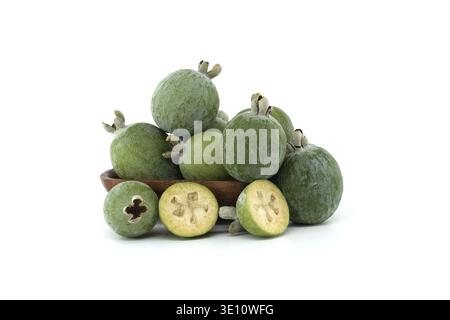 Collection de feijoas fraîches exposées dans un bol en bois sur fond blanc. L'image capture la couleur vibrante et la texture de ces tropicaux Banque D'Images