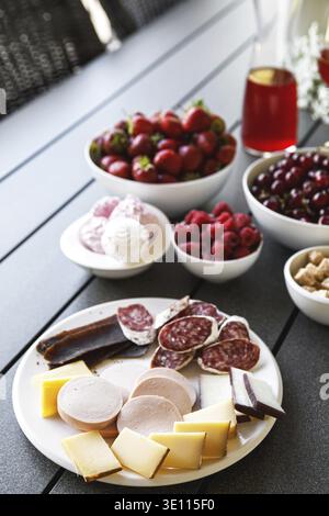 La table sur la terrasse d'été est pleine de collations. Fromage, saucisse, salami, viande et baies Banque D'Images