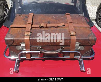 Valise en cuir portée avec sangles et boucles attachées au porte-bagages sur la voiture décapotable rouge classique évoquant le voyage et l'aventure Banque D'Images