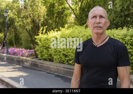 Senior homme chauve touristiques contre vue sur parc calme à Bangkok en Thaïlande Banque D'Images